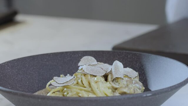 Food preparation. Slice of a black truffle falls on the spagetti pasta. Slow motion 4k video.