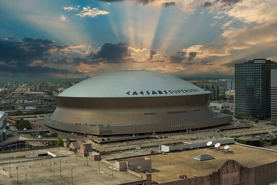 aerial shot of the Caesars Superdome and the Smoothie King Center with skyscrapers, office buildings and hotels in the city skyline and cars on the street in New Orleans Louisiana USA