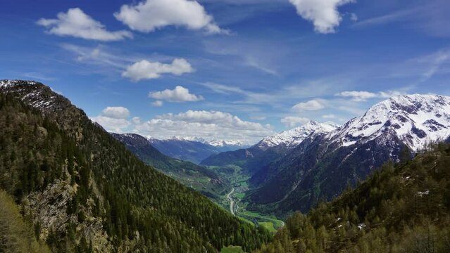 Beautiful top view of high snow-covered mountains and valley with road and village in Switzerland, zoom in timelapse 4k