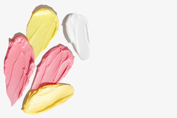 Pink, yellow and white cream smears on empty background