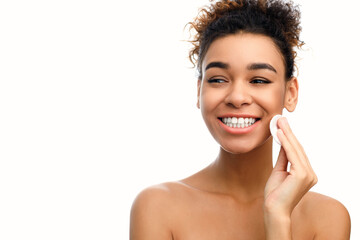 Happy woman cleansing her face with pad
