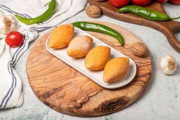 Uncooked frozen stuffed meatballs. Kibbeh or kibbeh on a wooden serving board