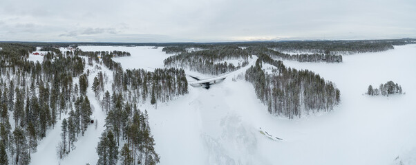 Aerial view over taiga landscape with snow covered boreal forest and frozen lakes in northeast Finland
