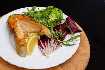 Wooden cutting board with white plate of meat and vegetables