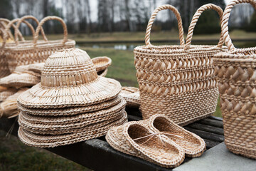 Straw-woven hats, baskets and bast shoes lie on the counter. Eco-friendly handmade products.