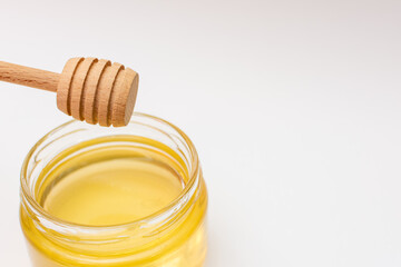 Wooden dipper in jar of honey, a liquid ingredient in a plastic bottle