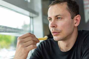 a man in a black shirt is eating french fries