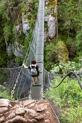 A woman is hiking on a suspension bridge in a wooded biome