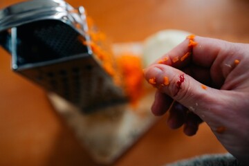 A woman cut her finger until it bled on a grater while cooking dinner.