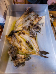 "View of a baking tray with a horse mackerel, a fish open and freshly cooked in the oven, ready to be served and eaten."