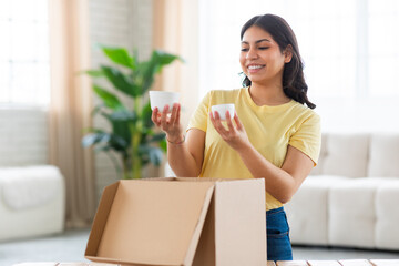 Contented woman looking at white mugs from a box