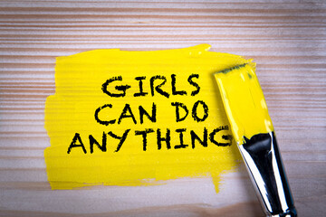 Girls Can Do Anything. Yellow paint and paint brush on wooden texture background - 790980588