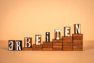 Work, word in German. Wooden alphabet letters on a light background - 790980956