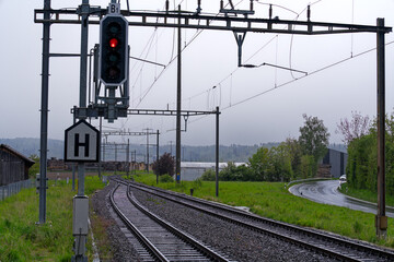 Railway station of Swiss village of Stammheim with tracks and overhead contact line on a rainy spring afternoon. Photo taken April 21st, 2024, Stammheim, Canton Zürich, Switzerland.