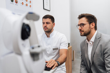 Attractive male doctor ophthalmologist is checking the eye vision of handsome middle age man in...