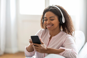 Woman with headphones using smartphone at home