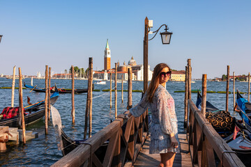 Tourist woman in dress watching gondolas moored by Saint Mark square in city Venice, Veneto,...
