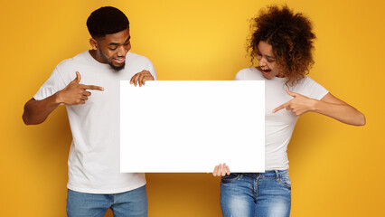 Young happy couple holding blank white board