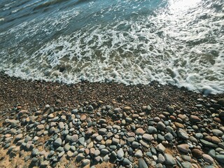 Tranquil Pebble Beach with Gentle Waves and Rocky Shoreline. Ideal for a Relaxing Getaway in the...