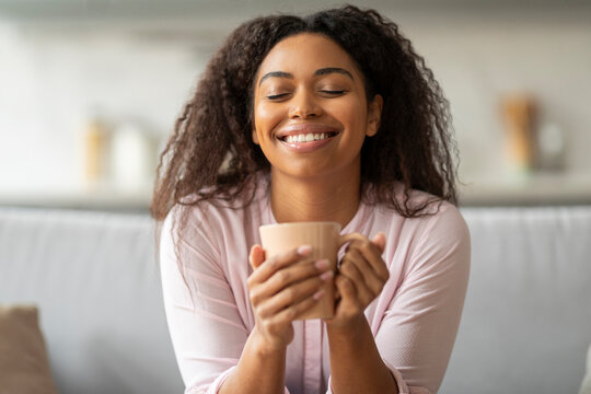 Happy woman sipping coffee on the couch