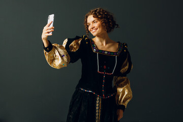 Portrait of a young aristocratic woman doing photo selfie with mobile phone and dressed in a medieval dress
