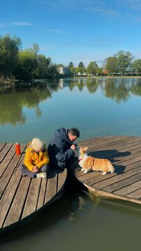 dad and son and their corgi dog playing on the pond