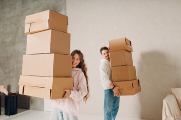 Happy young family couple man and woman carry cardboard boxes to new real estate apartment. Moving and delivery concept.
