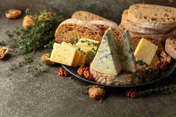 Cheese, bread, walnuts, and thyme on a stone kitchen table.