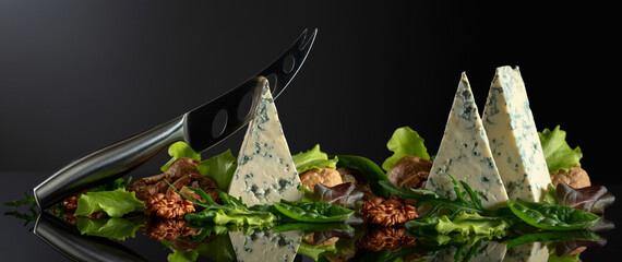 Blue cheese with knife, walnuts and fresh greens.