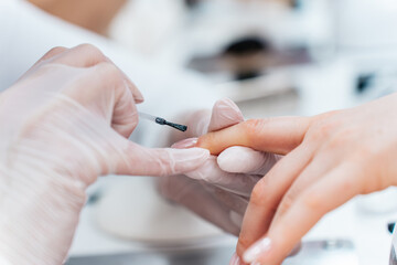 Professional manicurist working in a modern beauty salon. Satisfied female client receiving nail...