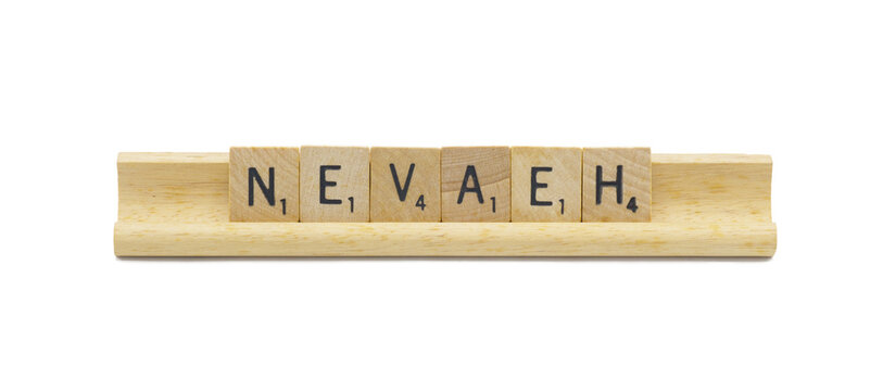 Miami, FL 4-18-24 popular baby girl first name of NEVAEH made with square wooden tile English alphabet letters with natural color and grain on a wood rack holder isolated on white background