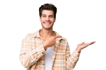 Young handsome caucasian man over isolated background holding copyspace imaginary on the palm to insert an ad