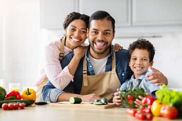 Family with child cooking and smiling at camera