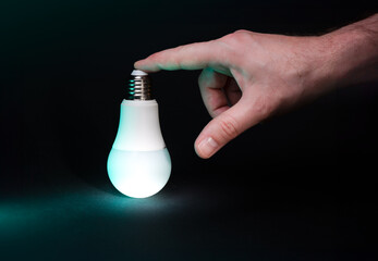 Hand holding glowing light bulb. Clean dark background. Ideas and solutions.