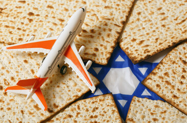 Airplane with orange wings and a white body, positioned on matzah bread pieces arranged to form a Star of David. This composition symbolizes travel and Jewish Passover celebration. Pesah celebration