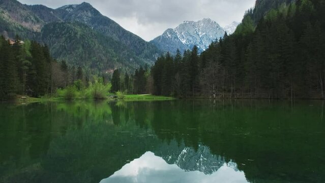 Alpine spring landscape with mountain lake. Plansarsko lake with green forest in Jezersko valley, Slovenia, Europe, 4k