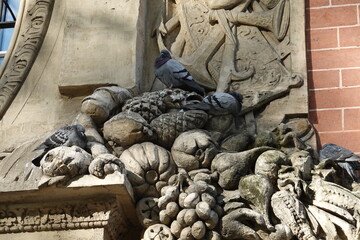 Pigeons qui se reposent dans une sculpture sur une façade - obrazy, fototapety, plakaty