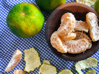 peeled ripe tangerine served in wooden bowl