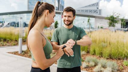 Focused athletes synchronize their smartwatches, preparing for a collaborative urban workout.