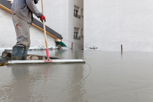 Process leveling floor after pouring concrete. Laborer leveling  concrete plate with square trowel on a construction site. Construction business, do-it-yourself, precision work on the house concept.