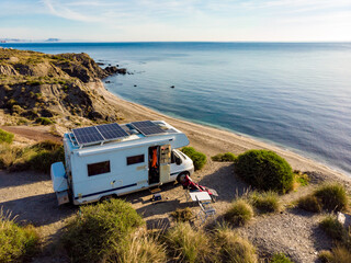 Caravan with solar panels on roof camp on sea, Spain. Aerial view.