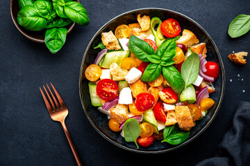 Summer vegetable salad with stale bread, tomatoes, cucumber, cheese, onion, olive oil, sea salt and green basil, black table background, top view - 791032131