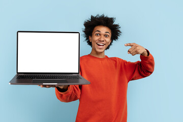 Man presenting blank laptop screen on blue background