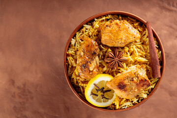 Chicken Biryani with Basmati Rice, Spices and Lemon on Brown Background, Top View, Copy Space