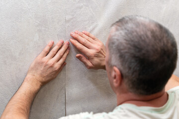 A man is gluing non-woven wallpaper on the wall. Room renovation