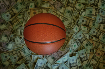 Basketball on a pile of cash -- sports betting concept - obrazy, fototapety, plakaty