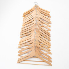 20 Kleiderbügel aus Holz in einer Reihe auf weißem Untergrund, senkrecht liegend. - obrazy, fototapety, plakaty