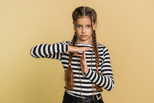 Tired serious upset young preteen child girl kid showing time out gesture, limit or stop sign, no pressure, I need more time, take a break, relax, rest, help. Teenager children on beige background