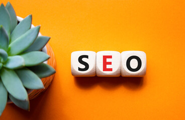SEO - Search Engine Optimization symbol. Wooden blocks with words SEO. Beautiful orange background...