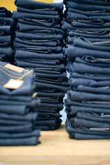 A pile of raw denim jeans fresh off a production line in a denim factory. Industrial fabric and fashion manufacture. Stylish blue denim fabric for wholesale.